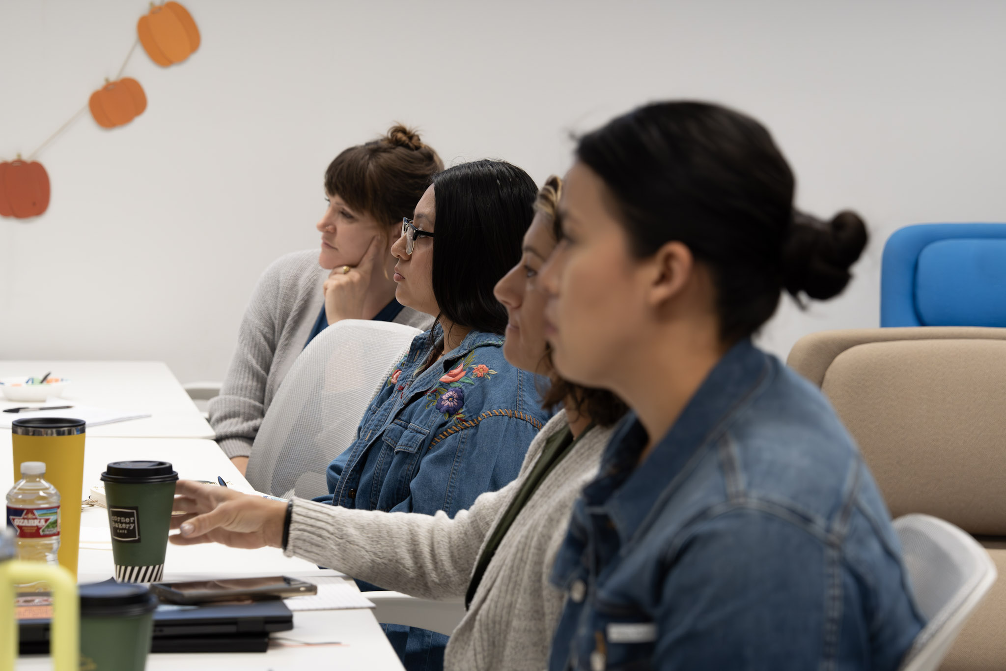 Four people seated at a conference table, listening attentively during a meeting or workshop.